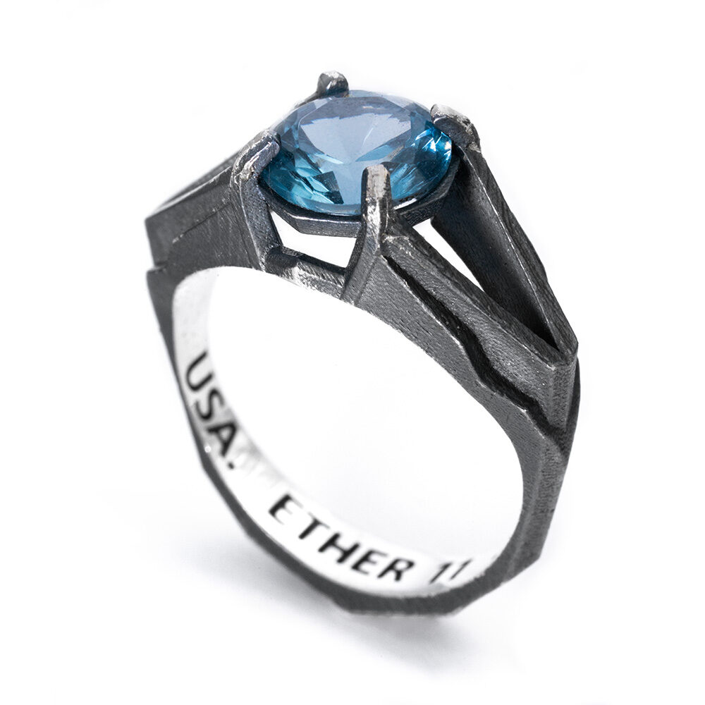 Angled view of the Antimatter Ring showing the split shank and faceted Paraiba tourmaline against blackened sterling silver.