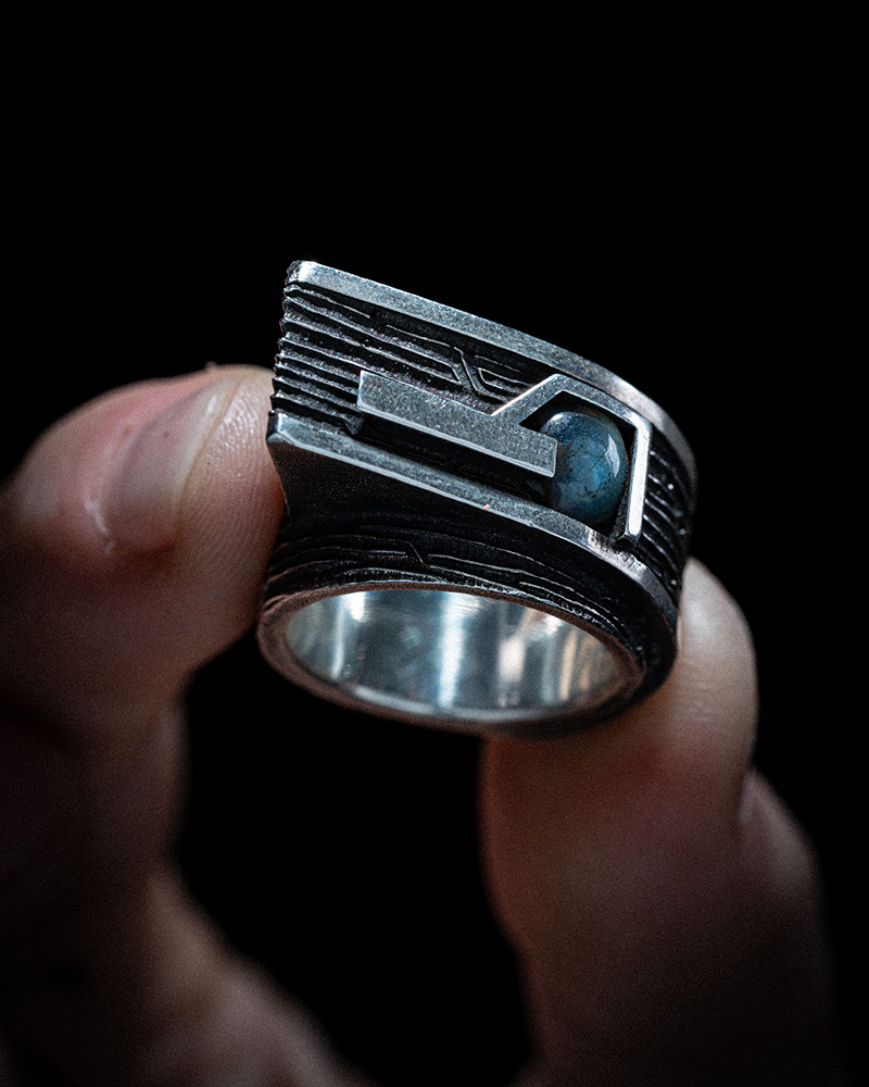 Gravity Ring held in hand from above, showing the labradorite cabochon set into the ring's geometric top face.