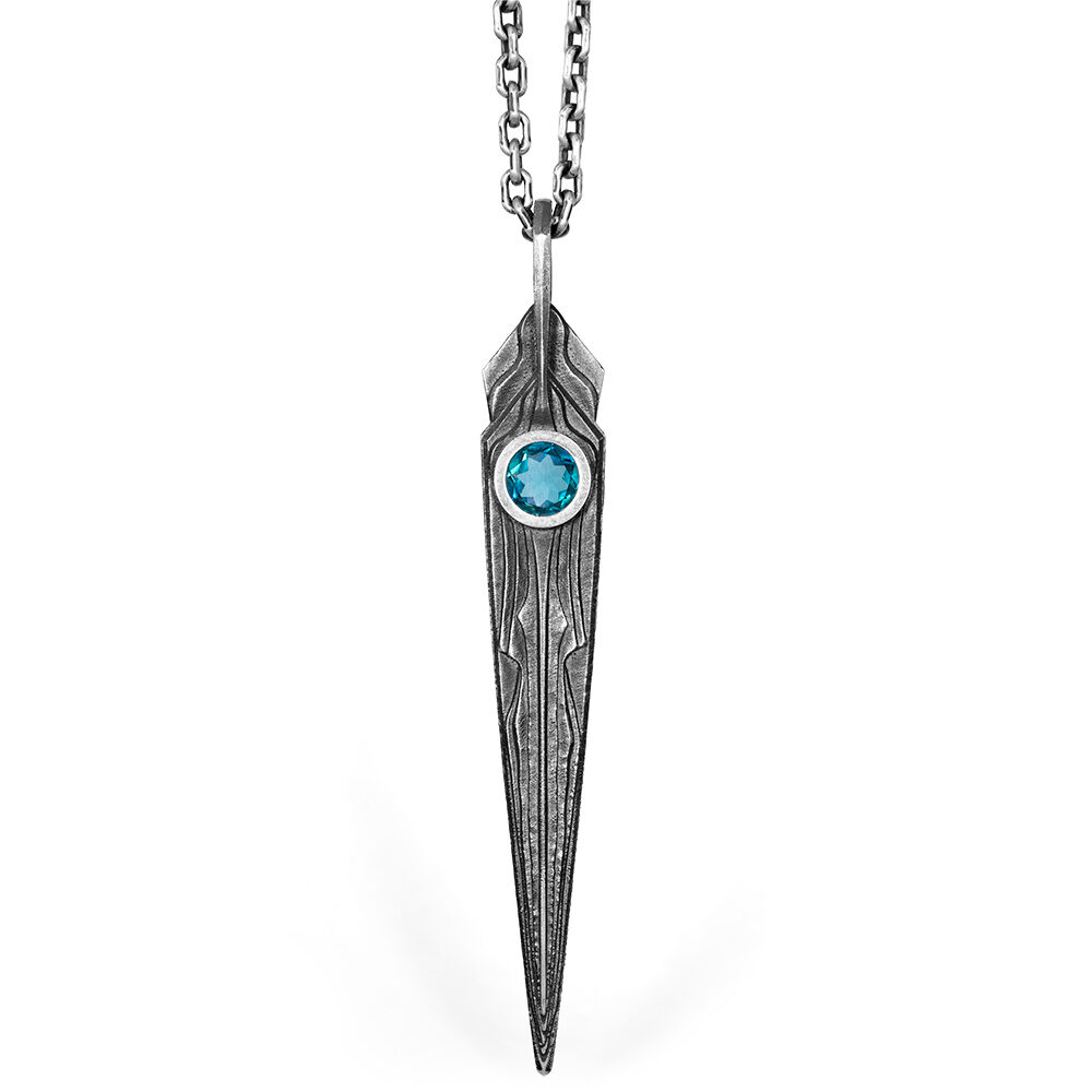 Needle Necklace 3i — hero The Needle Necklace 3i in oxidized sterling silver, a tapered blade pendant set with a faceted blue stone, by Ether Eleven.