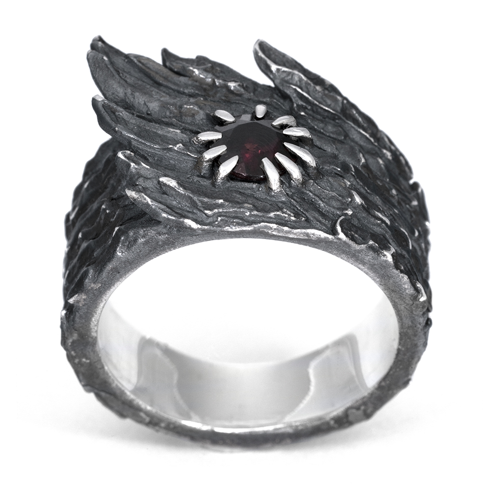 Front view of the Stone Wing Ring showing the garnet held in asymmetric spiked prongs against carved rock texture.