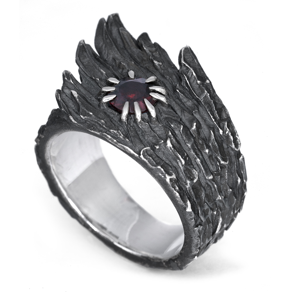The Stone Wing Ring in oxidized sterling silver, a wing-shaped band set with a natural garnet in spiked claw prongs, from the Ether Eleven Terra collection.